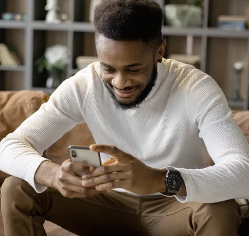 Person smiling at a phone on a sofa